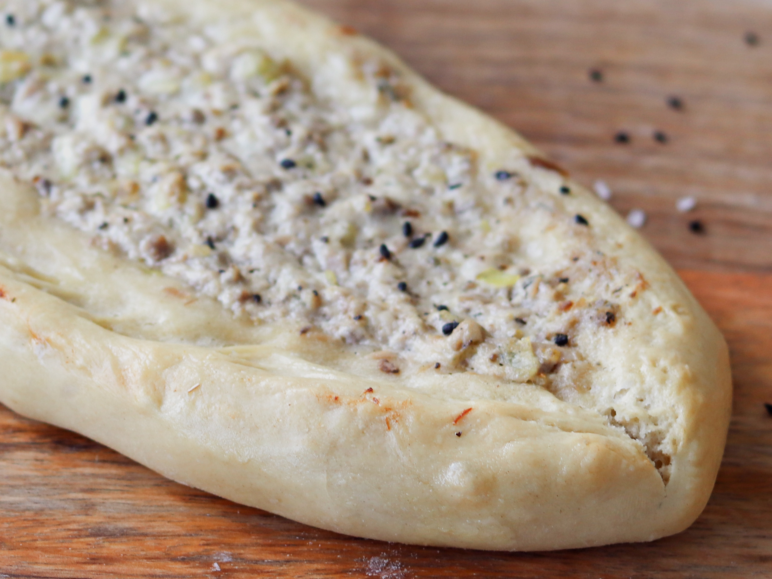 Türkisches Germteiggebäck mit Thunfischbelag auf einem Holzbrett